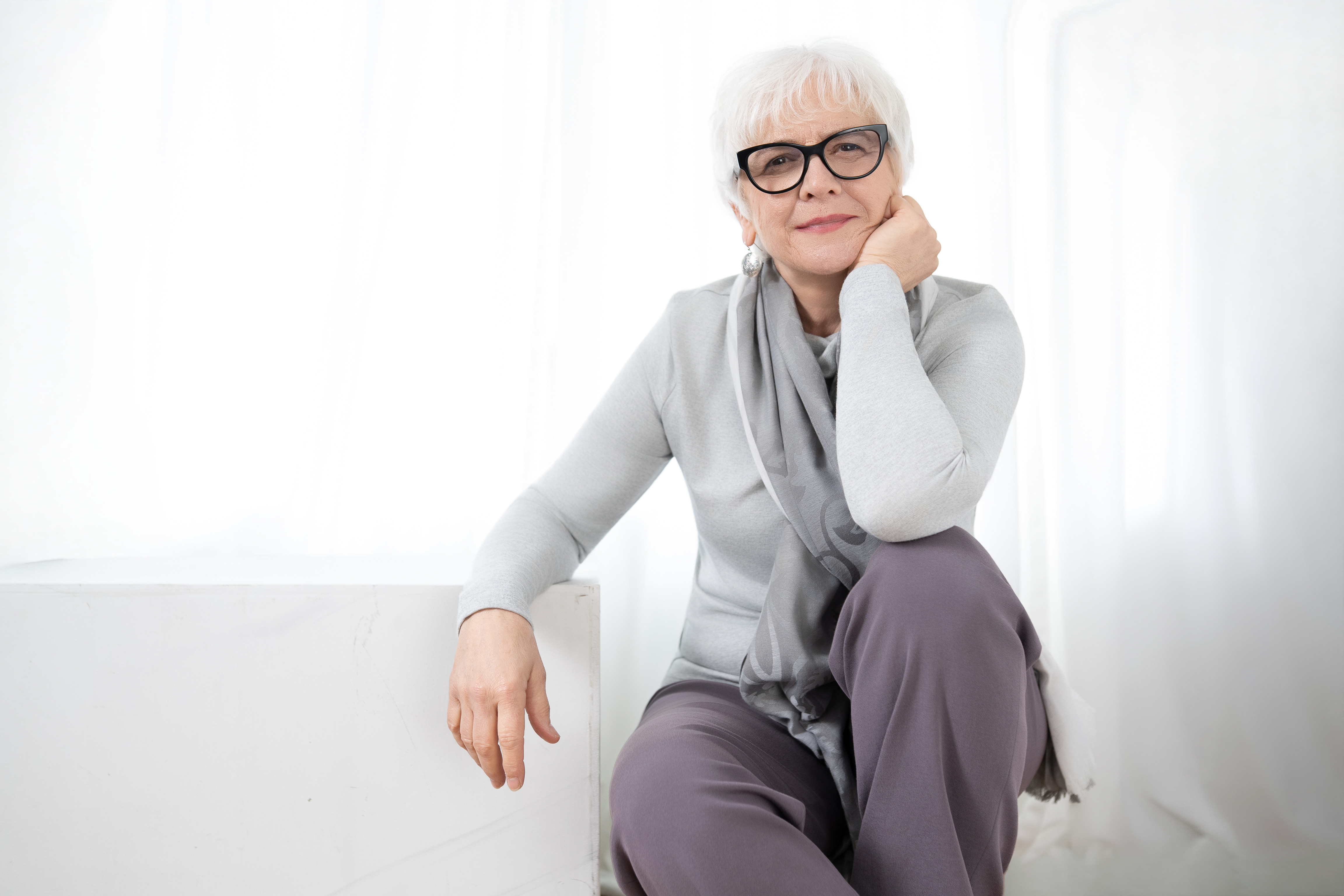 Portrait of Joan Szymko wearing light colors in a white room